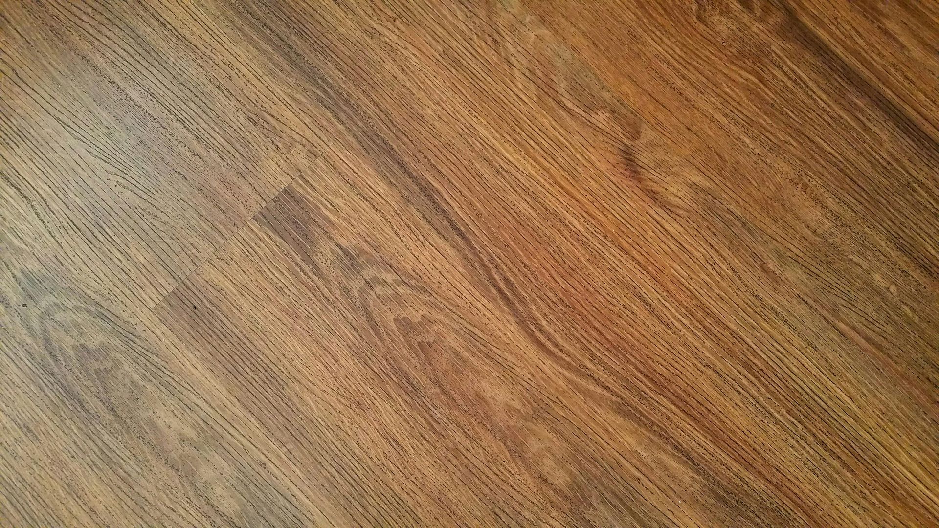Wood-grain flooring, angled, with a mix of light and dark brown tones.