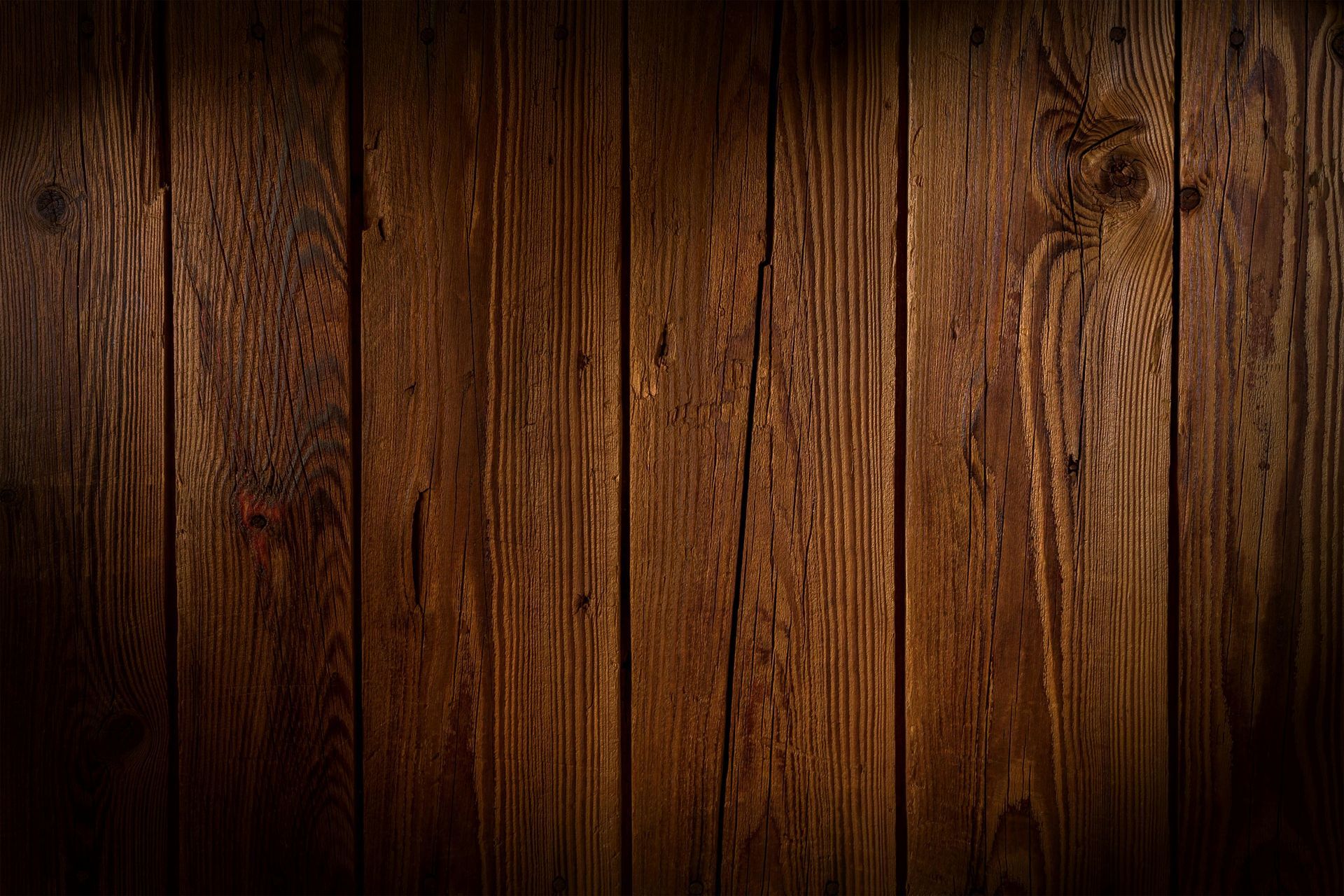 Dark brown wooden planks, vertical grain, with light and shadow creating texture.