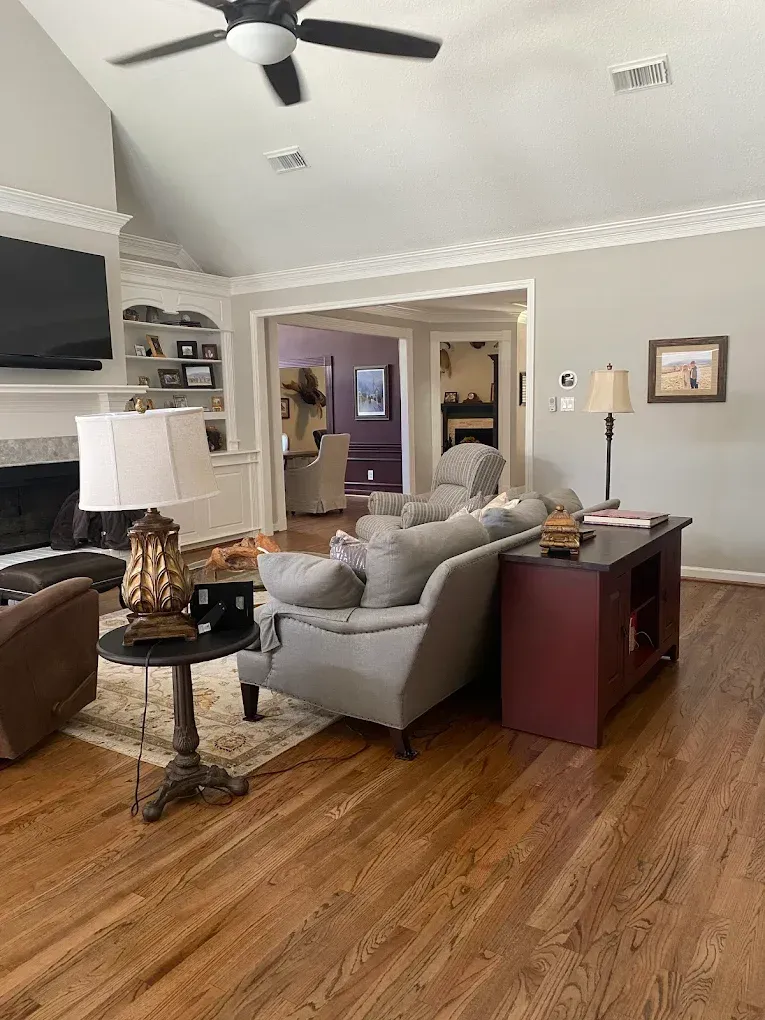 Living room with hardwood floors, gray walls, and furniture, including a sofa and end tables.