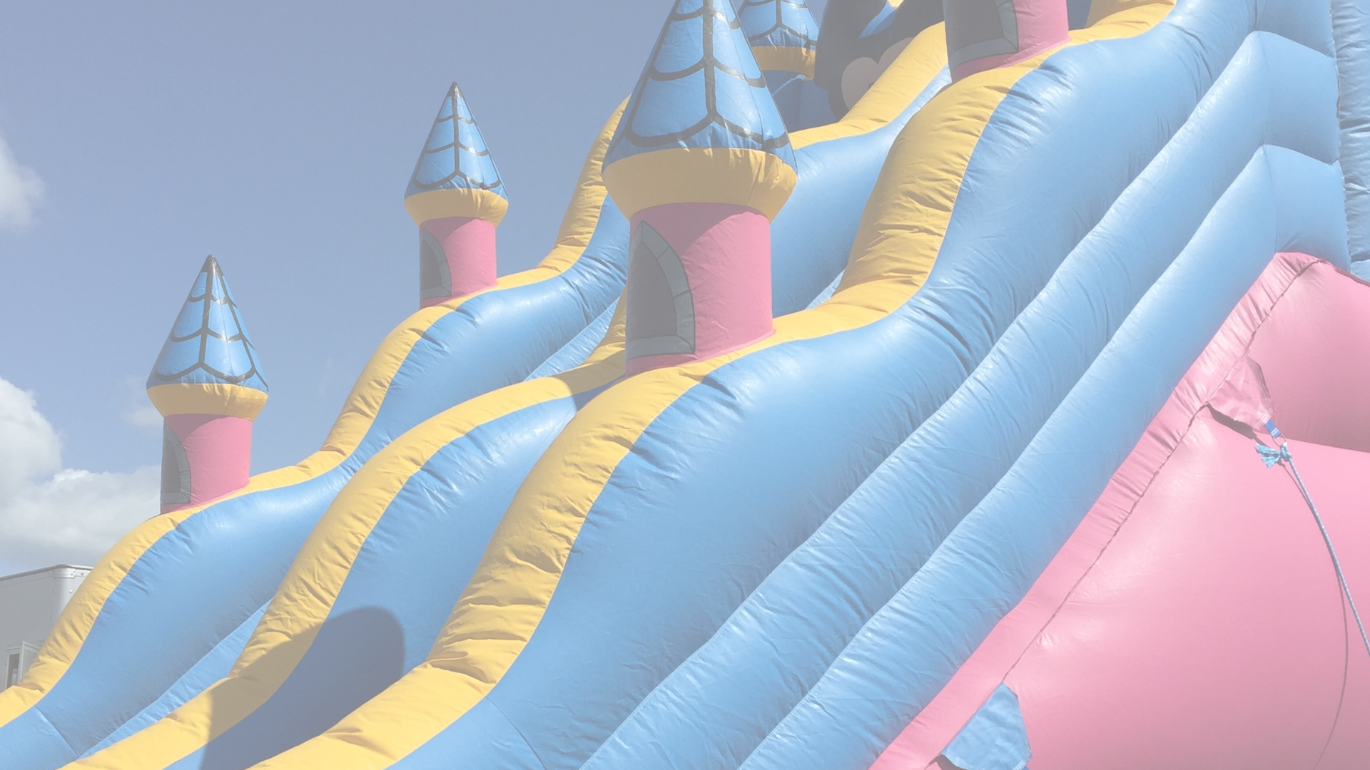 A pink and blue inflatable slide with a blue sky in the background.