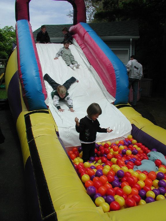 Children are playing on an inflatable slide in a ball pit