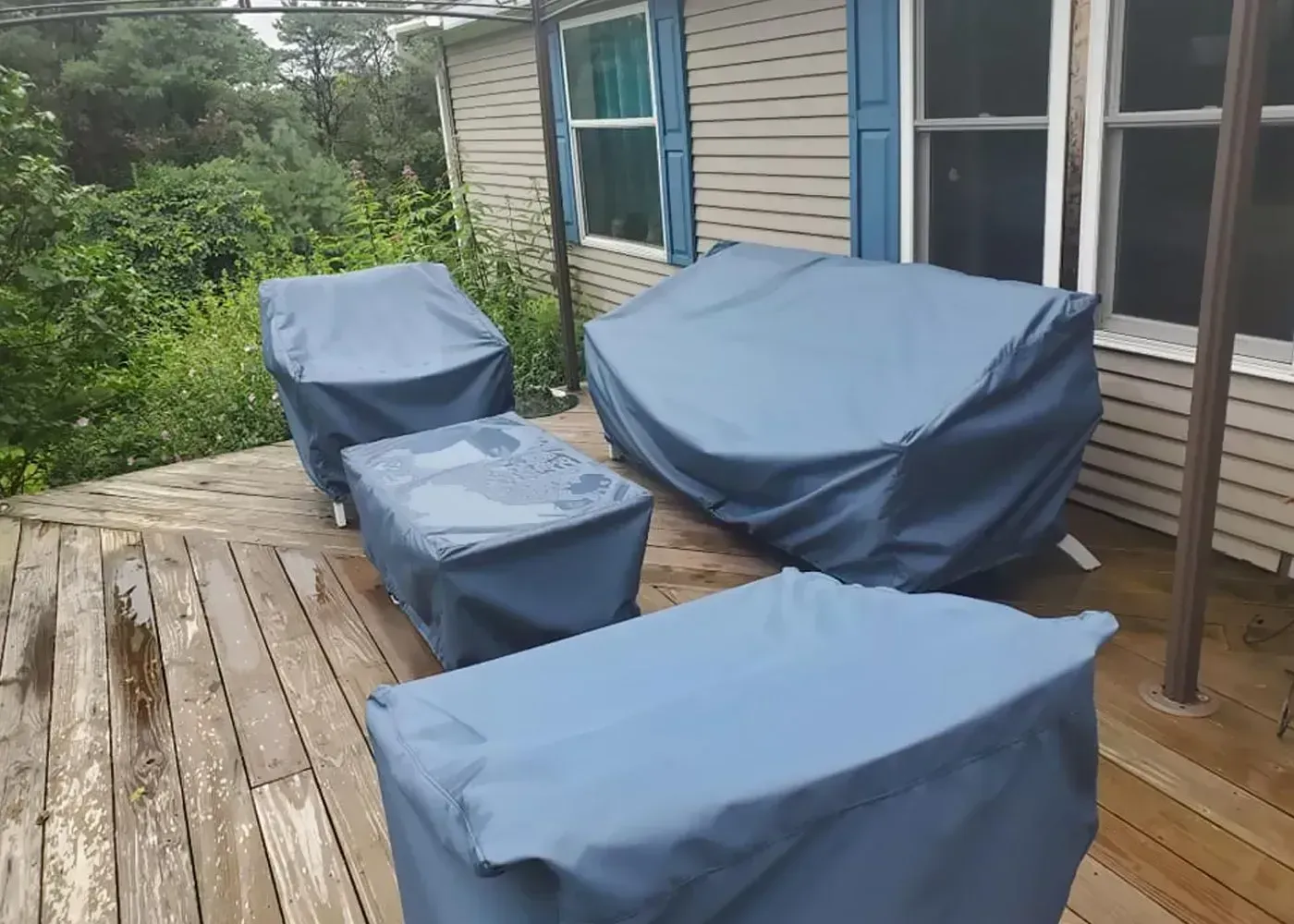 A deck with a couch and chairs covered in blue covers