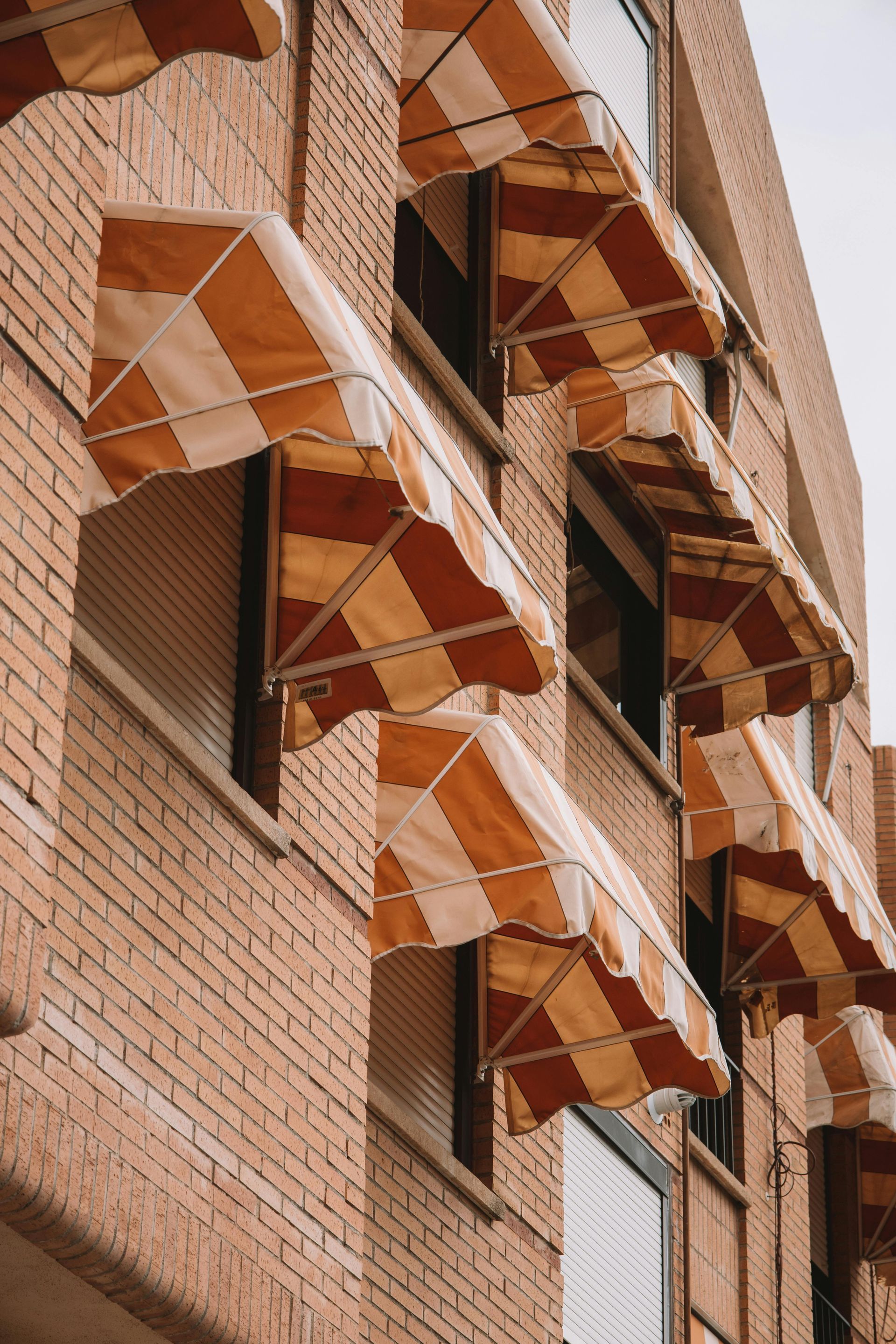 A brick building with a lot of awnings on the windows.