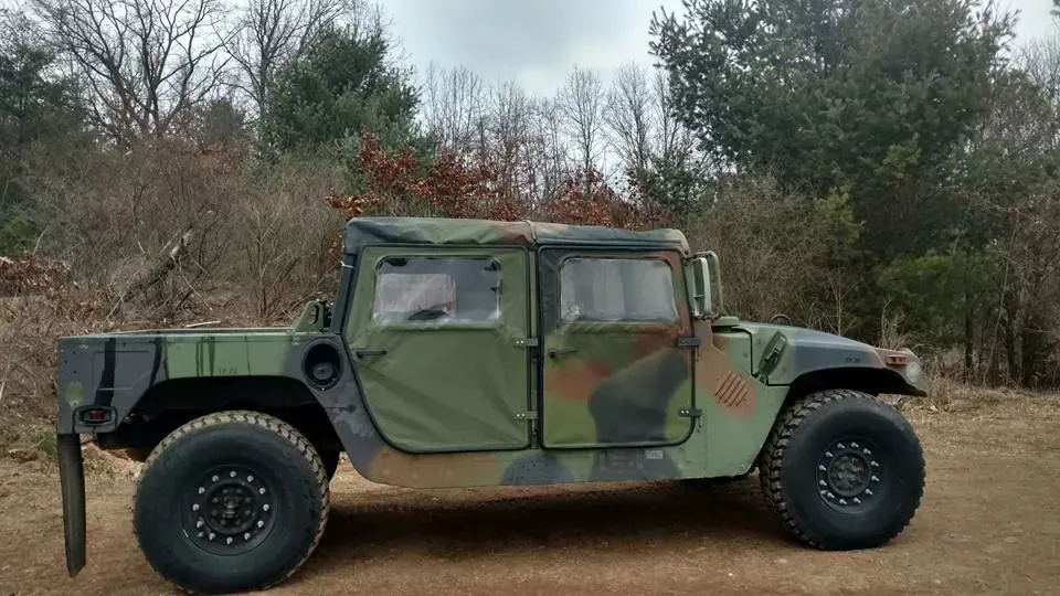A military vehicle is parked in a dirt field.