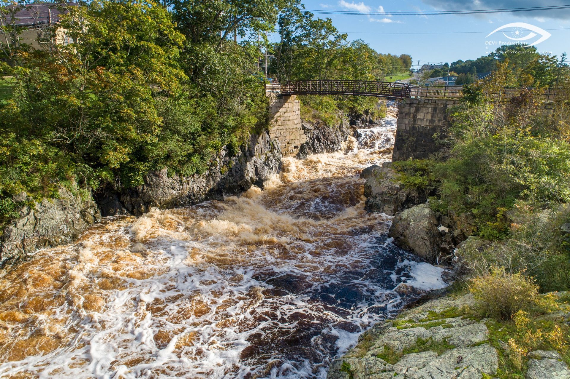 A bridge over a river surrounded by trees and rocks.