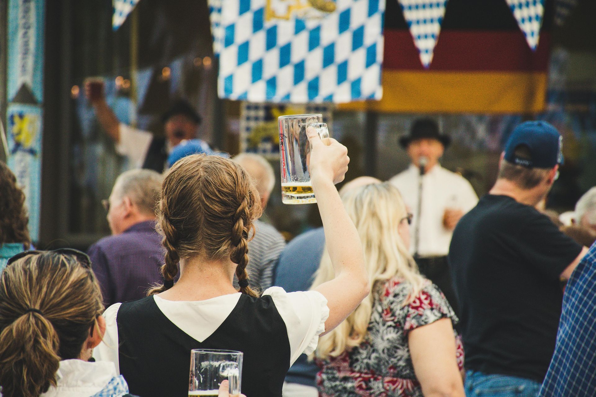 girl olding up a glass of beer while at an octoberfest festival 