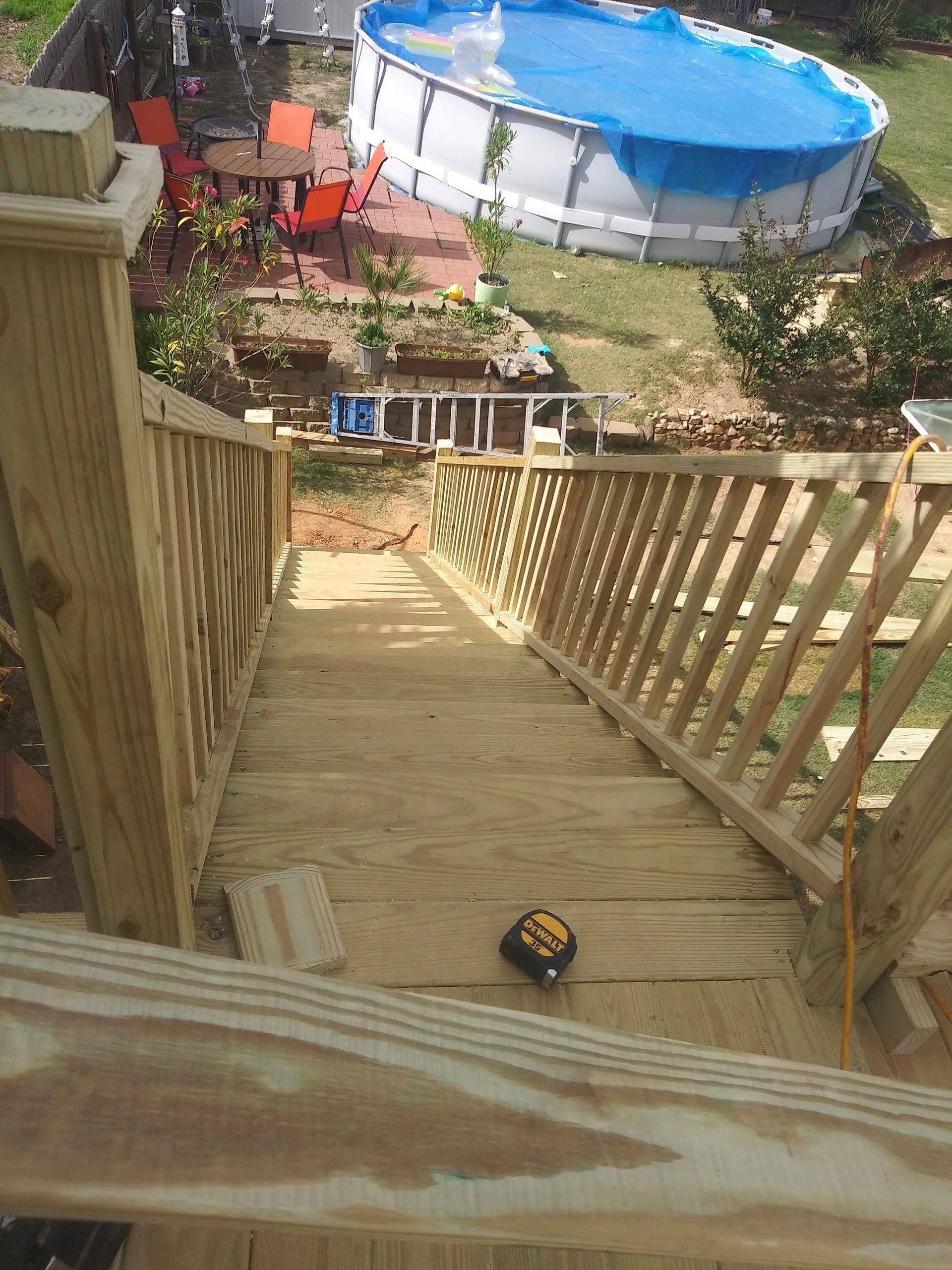 Wooden outdoor stairs leading down to a backyard with a pool.
