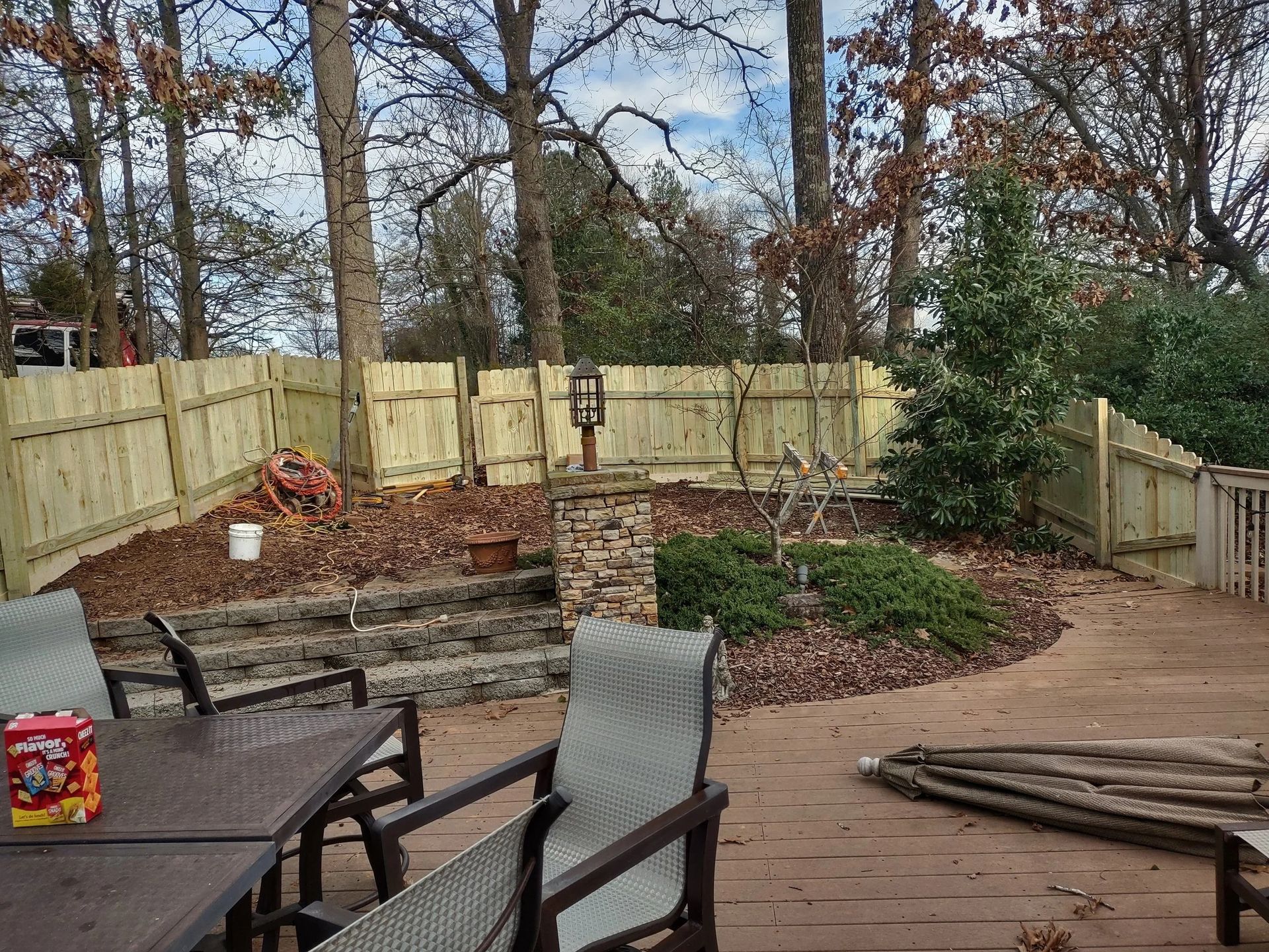 Backyard with wooden fence, stone steps, patio furniture, and trees.