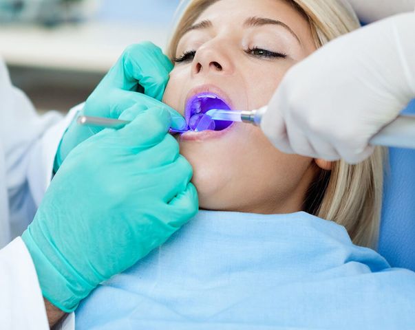 A woman is getting her teeth examined by a dentist