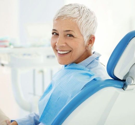 A woman is smiling while sitting in a dental chair