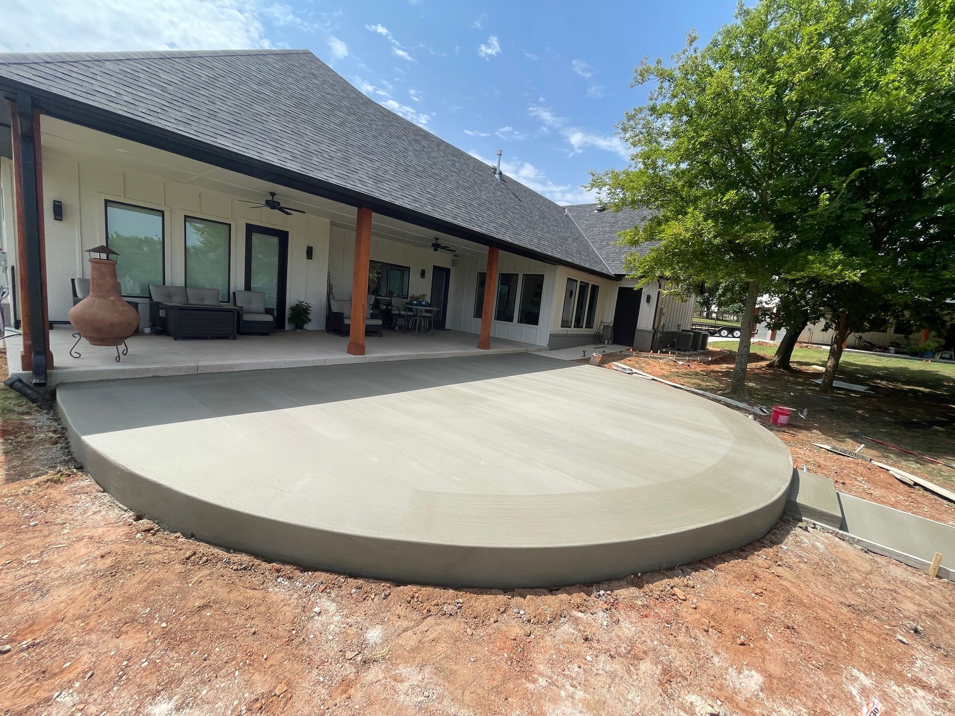 Newly poured concrete patio next to a house with a dark roof.