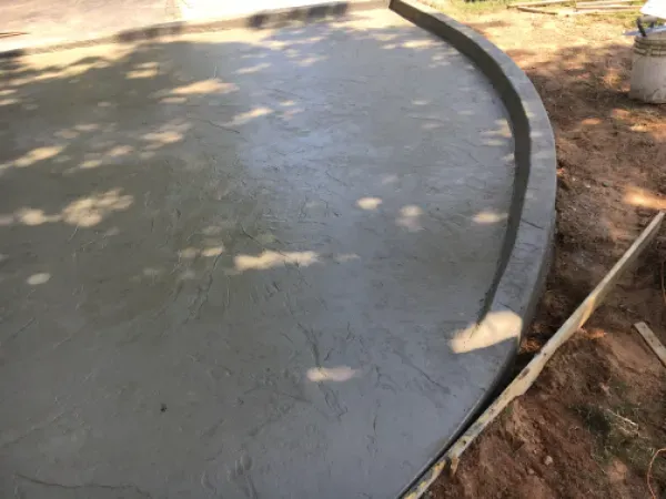 Newly poured concrete patio with a curved edge.