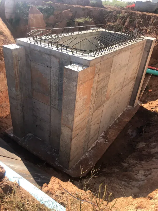 Concrete rectangular structure with rebar, set in an excavated area; construction site.