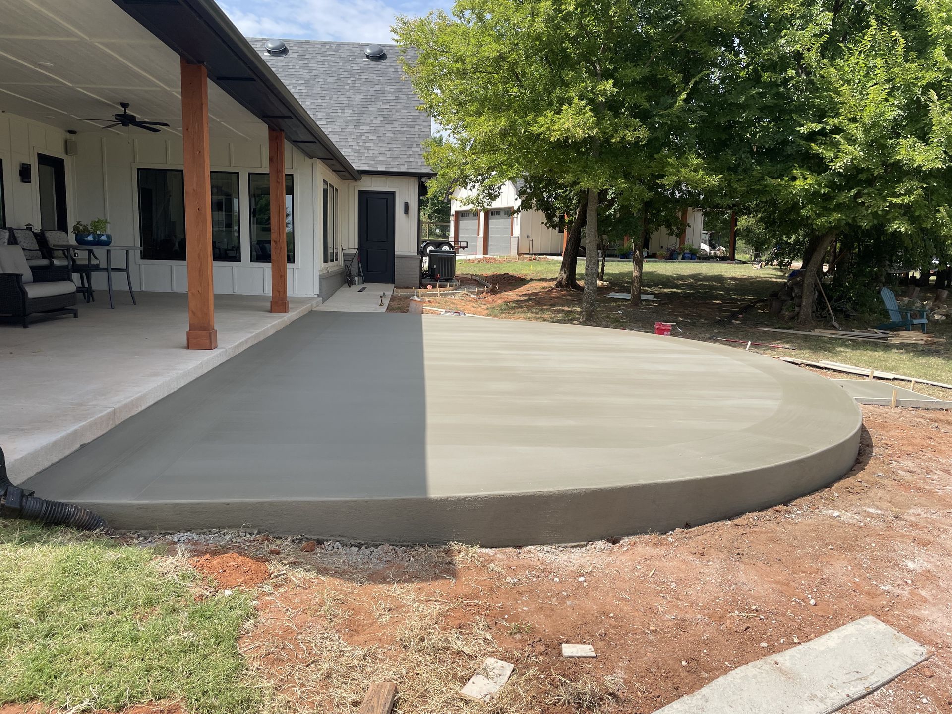 Newly poured concrete patio next to a house with a covered porch.