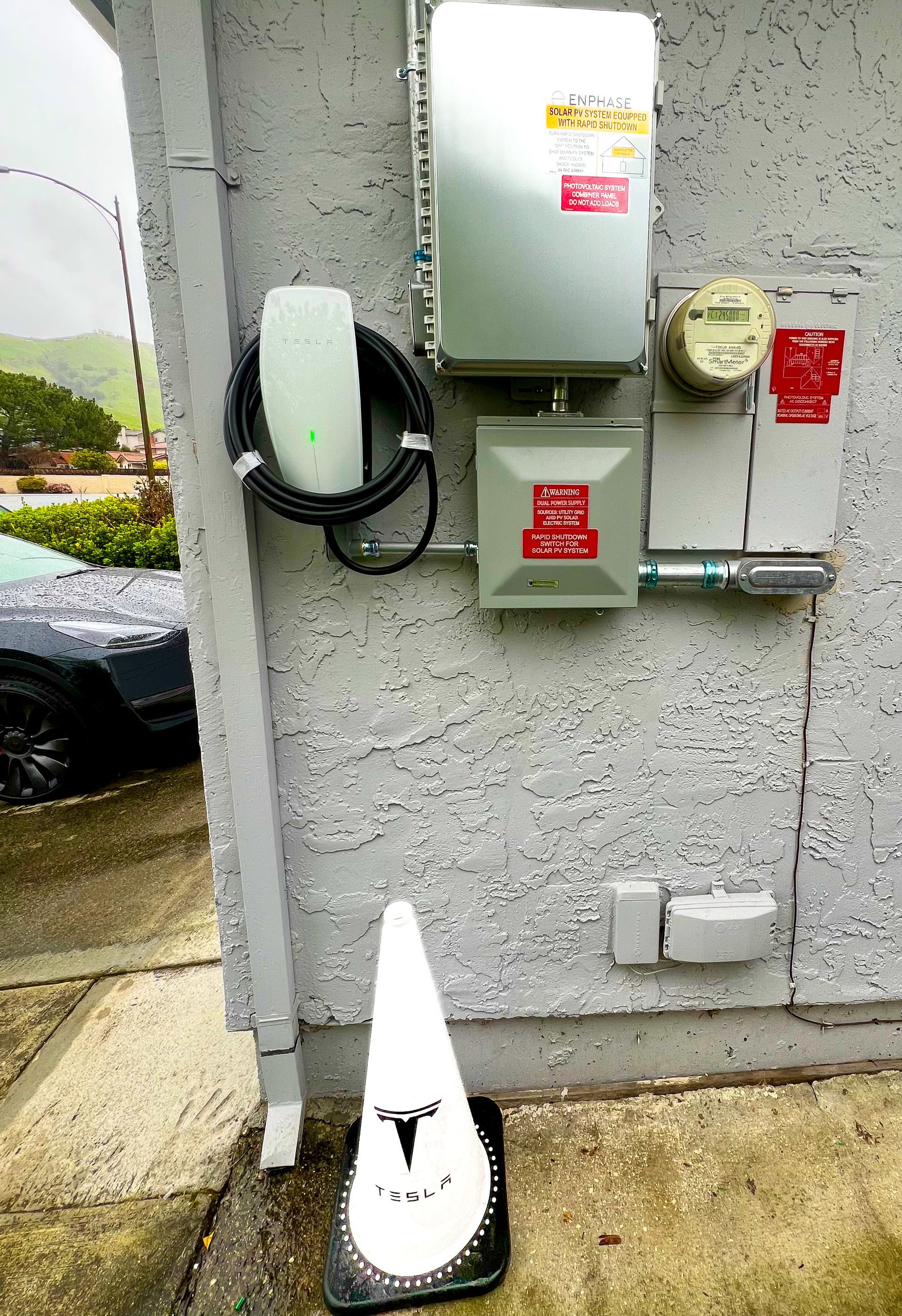 A car is being charged at a charging station on the side of a building.