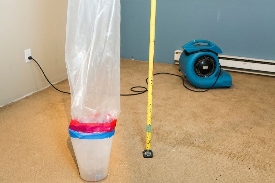 Blue air mover and plastic containment barrier set up for drying in a carpeted room