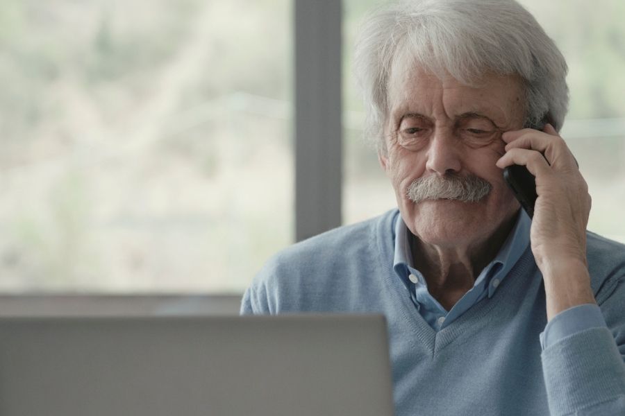 Homeowner making a phone call while sitting at a laptop after storm damage