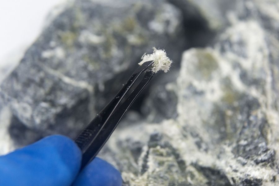 Asbestos fibers held by tweezers during lab analysis of a building material sample