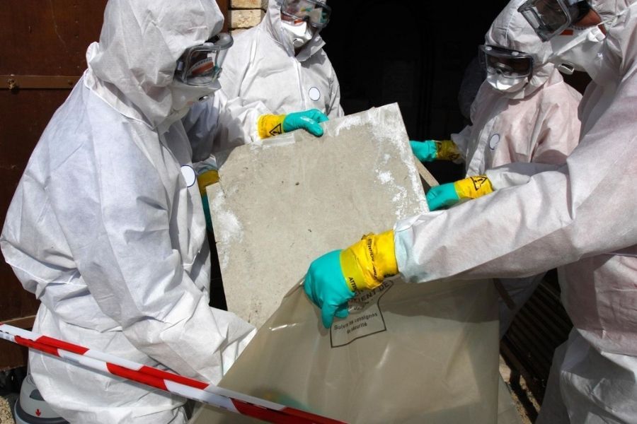 Asbestos removal workers wearing full protective suits and respirators
