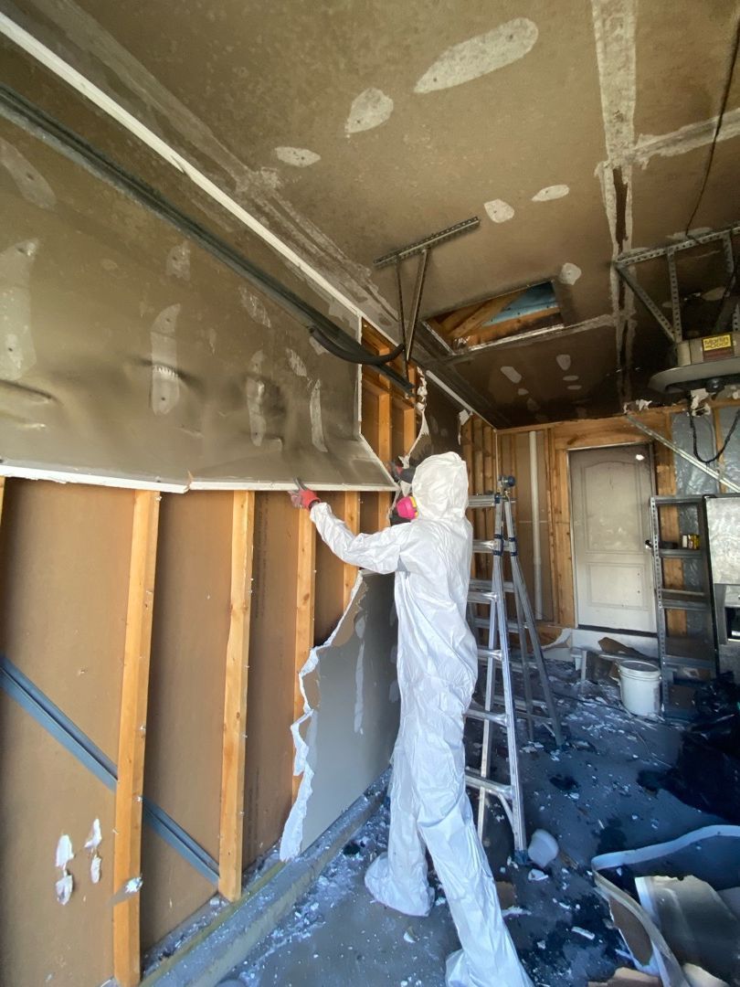 Restoration worker performing ceiling removal during fire damage demolition in St. Louis home