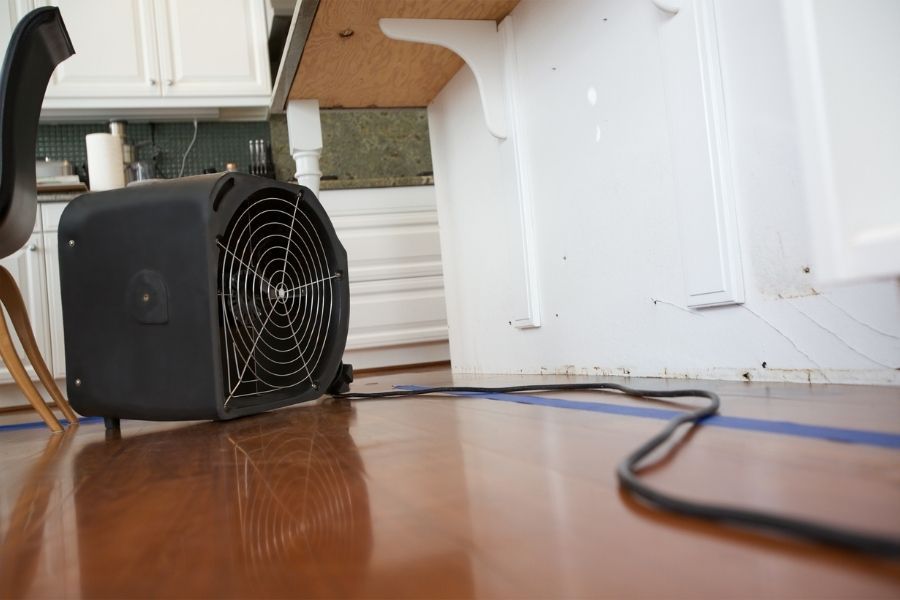 Professional drying equipment set up on water-damaged hardwood kitchen floor