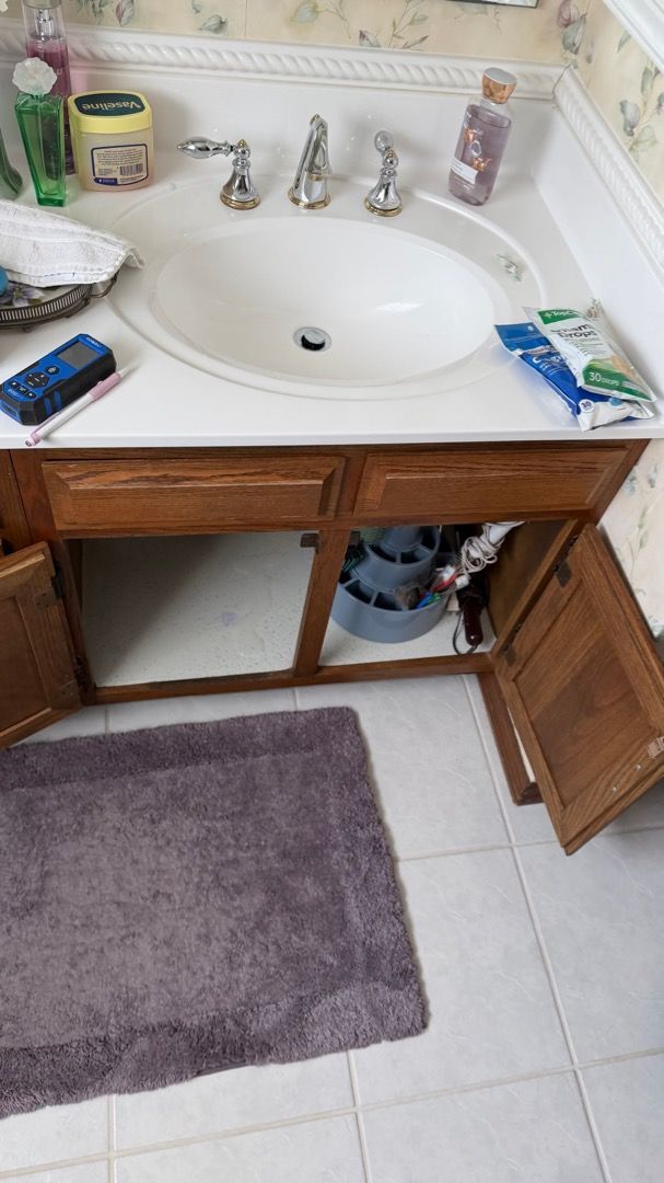 Close-up view of the loose P-trap under the bathroom sink causing the water damage
