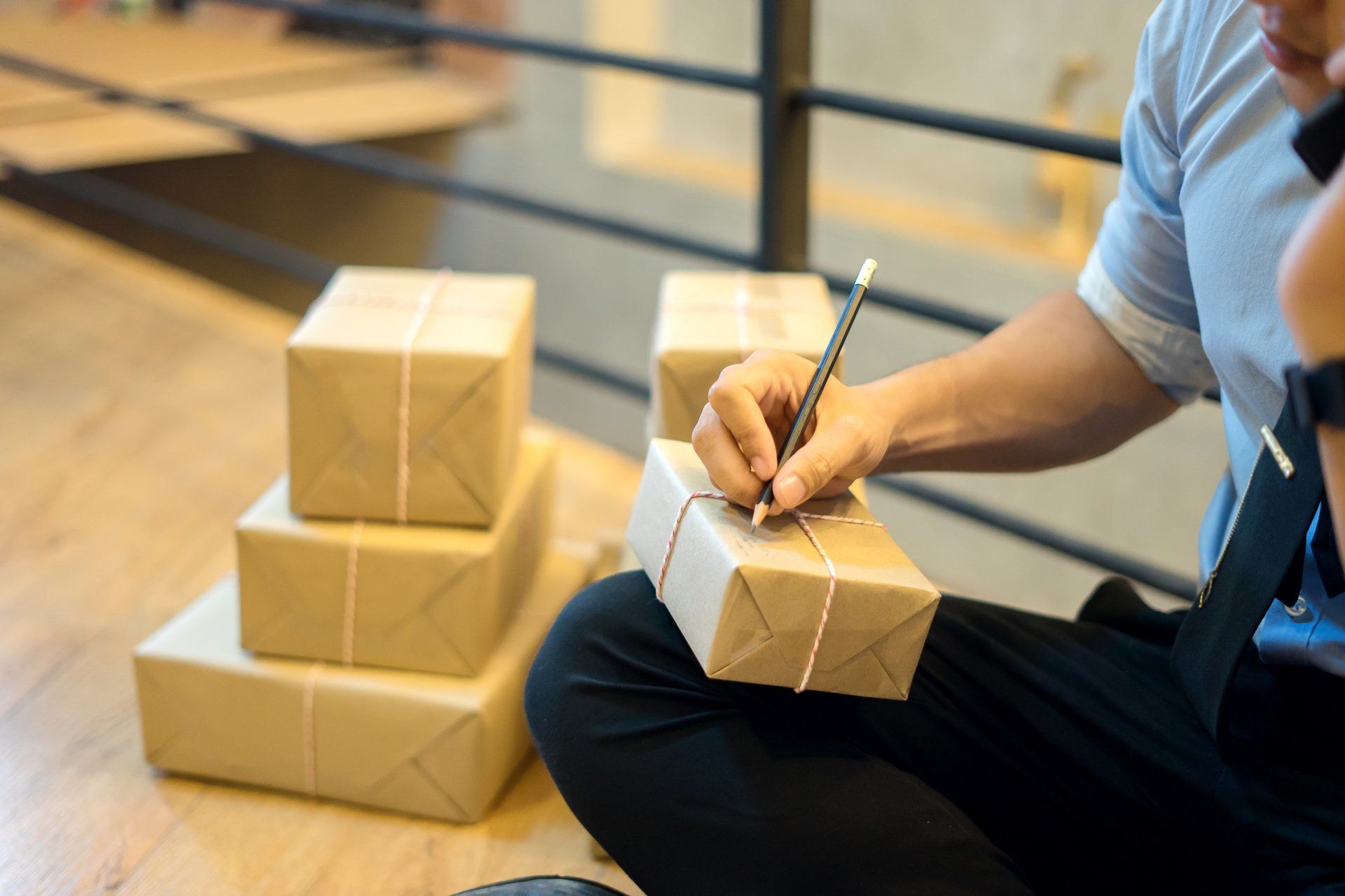 A man is sitting on the floor writing on a box.
