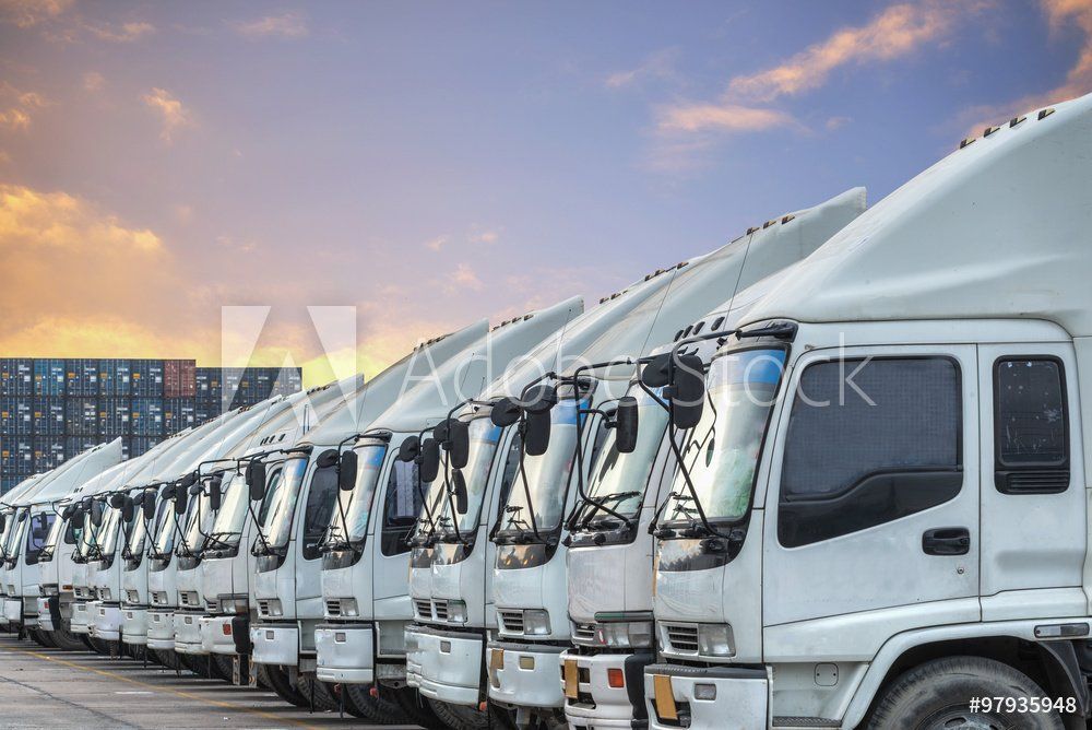 A row of white trucks are parked in a parking lot.