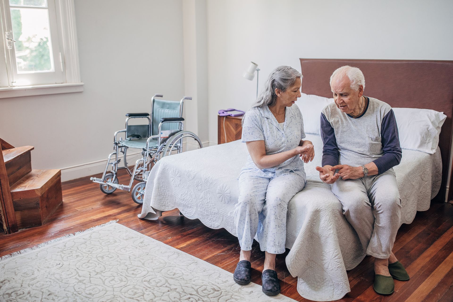 Wheelchair lift outside a home, providing access to the porch.  White and silver metal structure. Green wall and natural stone patio.