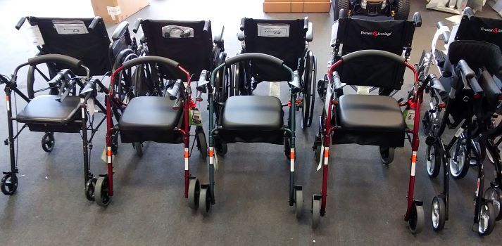 Several rolling walkers of various colors lined up.