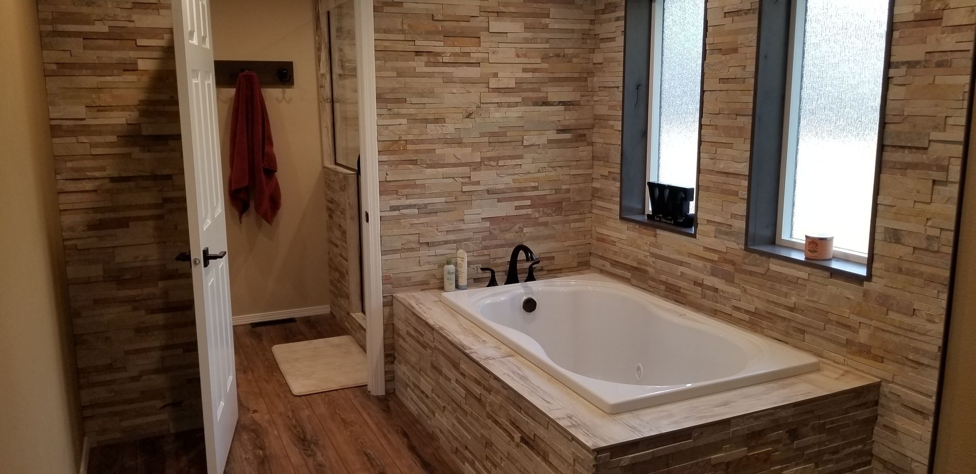Bathroom with a bathtub, textured tile walls, and a glass shower door.