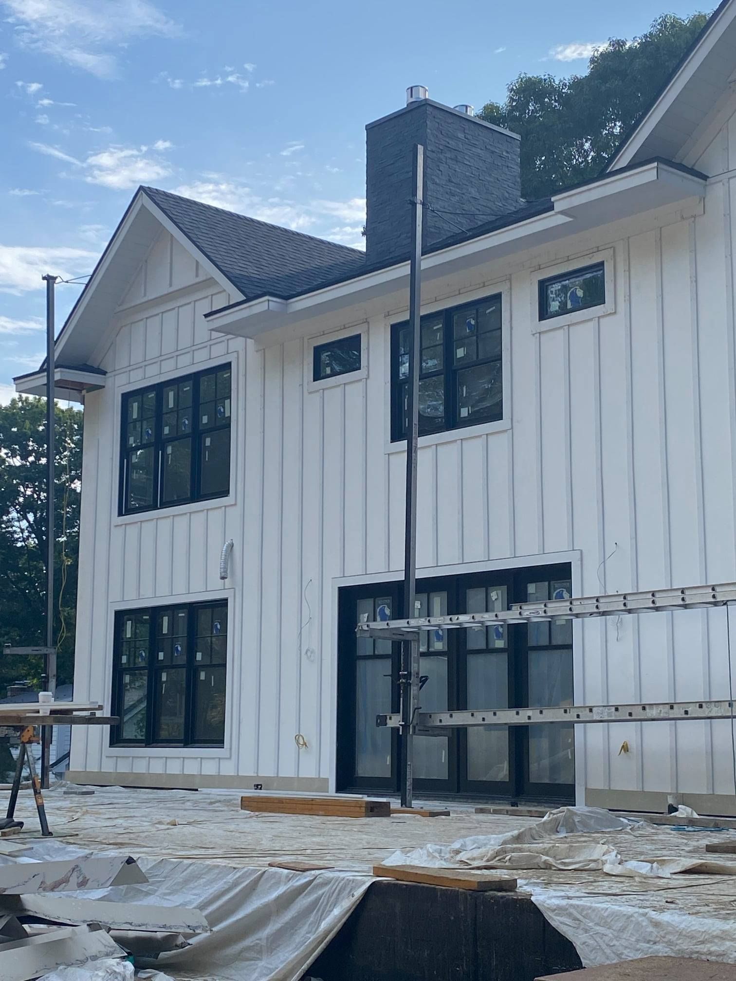 White house under construction with black windows and chimney.