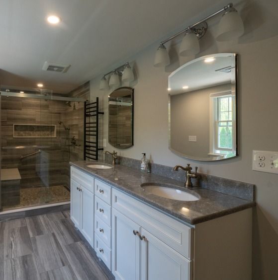 Bathroom with a white vanity, two sinks, mirrors, and a glass shower.