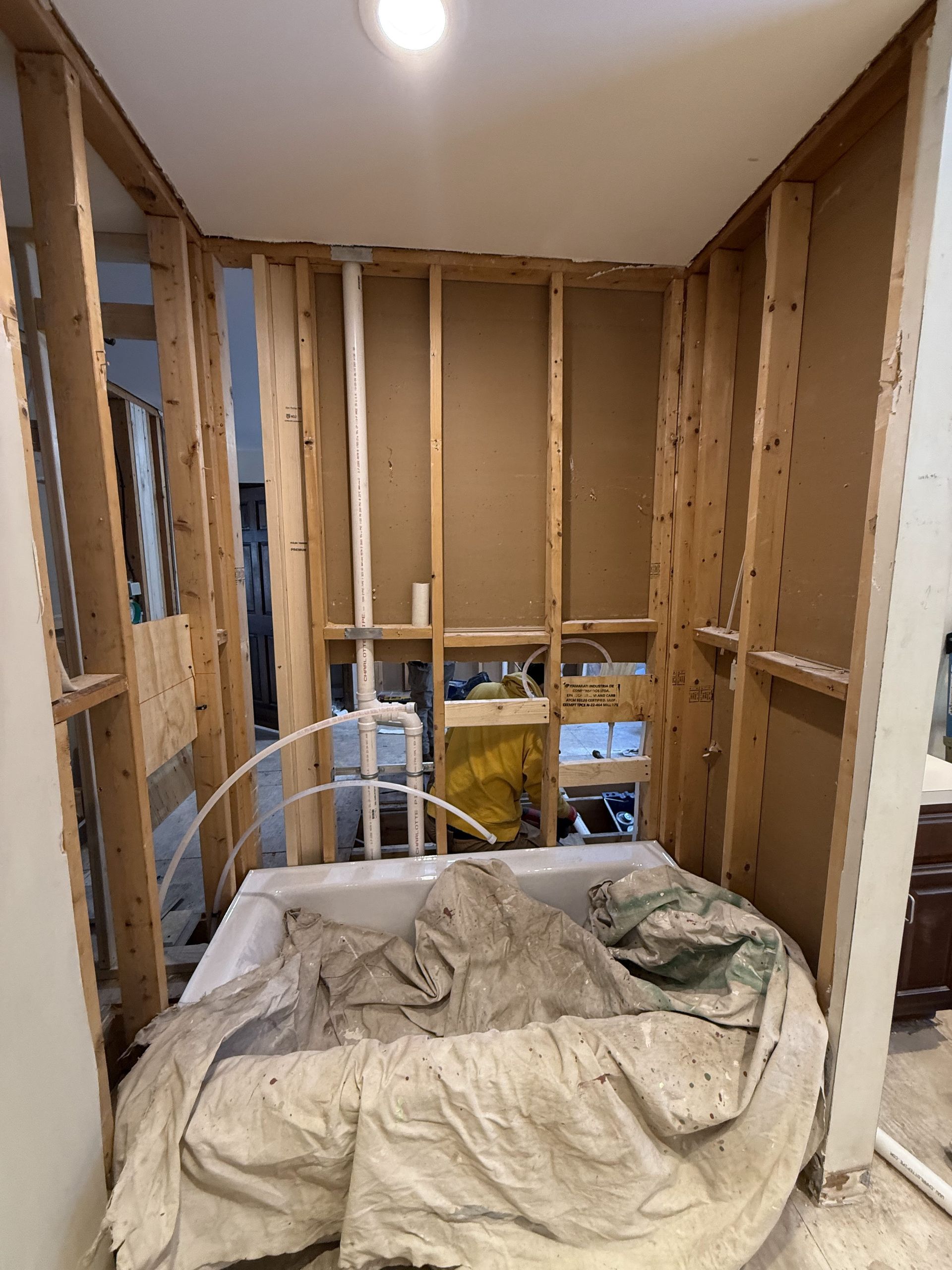 Bathroom renovation in progress, framing around a bathtub, exposed pipes, and insulation.