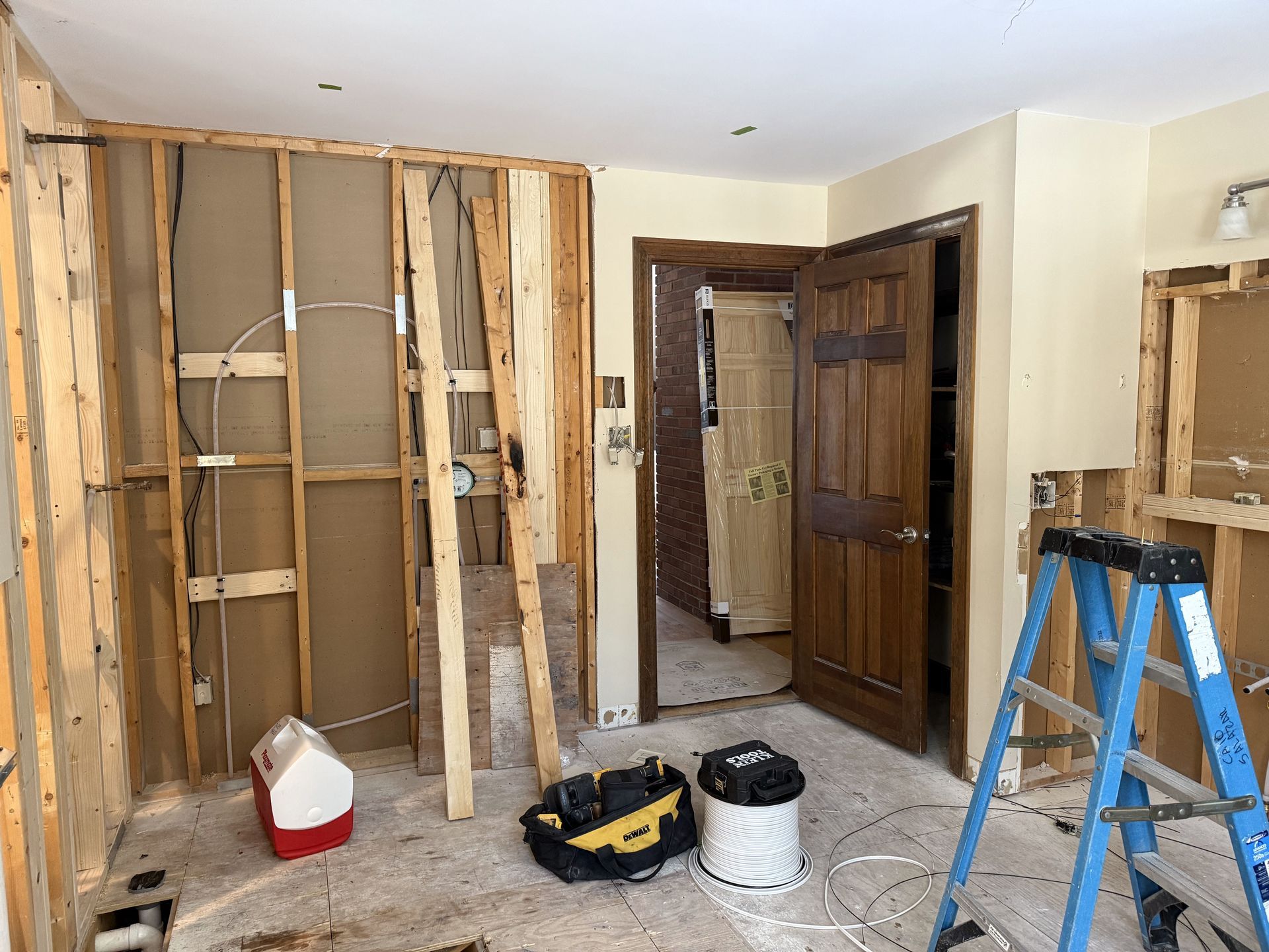 Room under construction with exposed wall studs, tools, and a doorway.