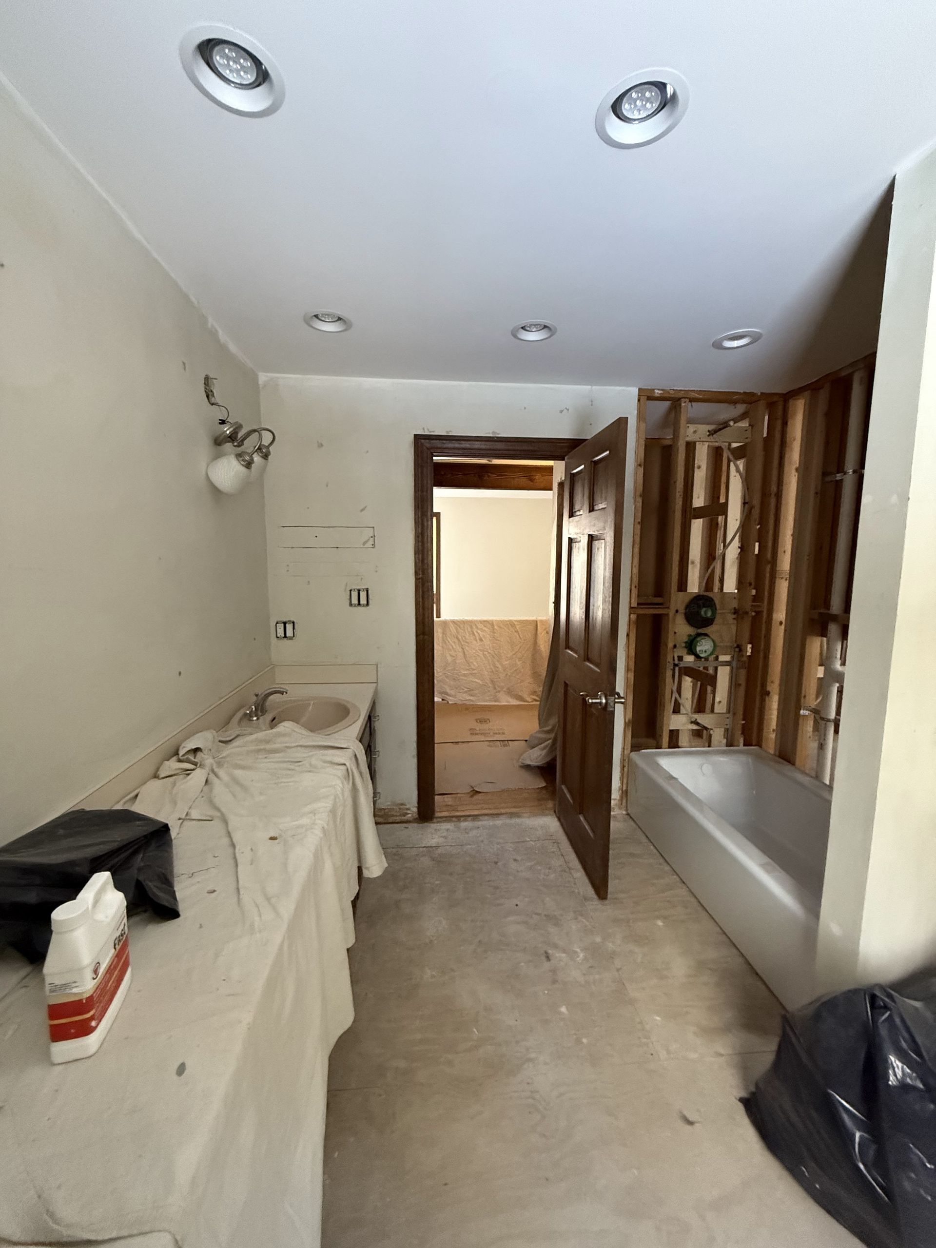 Bathroom under renovation with exposed wall studs, tub, and partially removed fixtures.