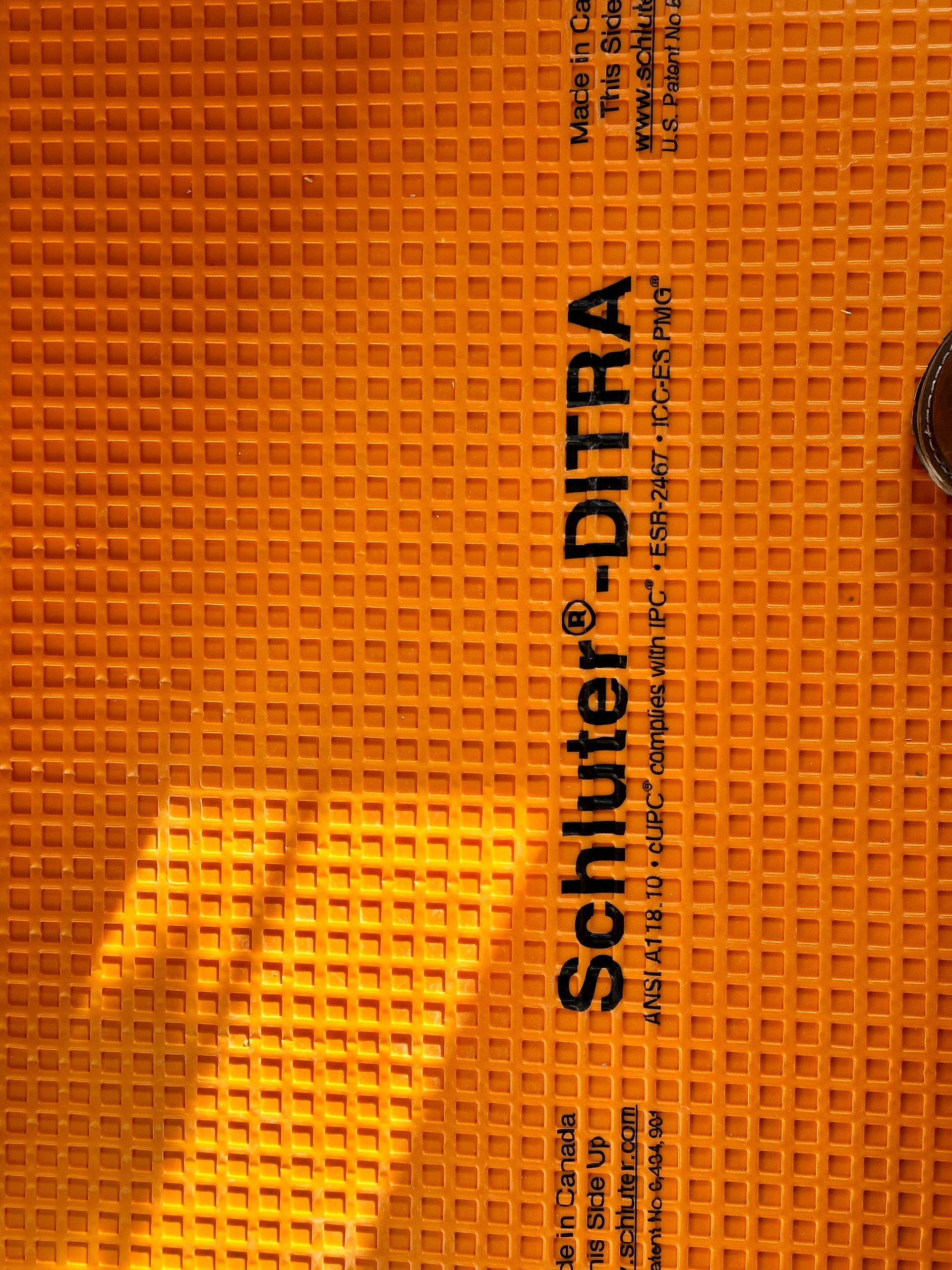 Orange Schluter-DITRA membrane with a grid pattern for tile installation.