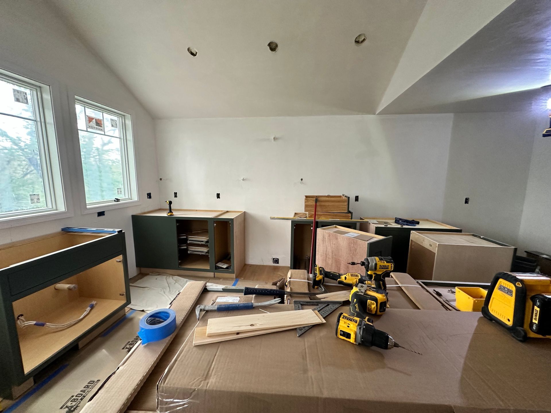 Kitchen under renovation, cabinets in various stages of assembly, tools scattered on countertops.