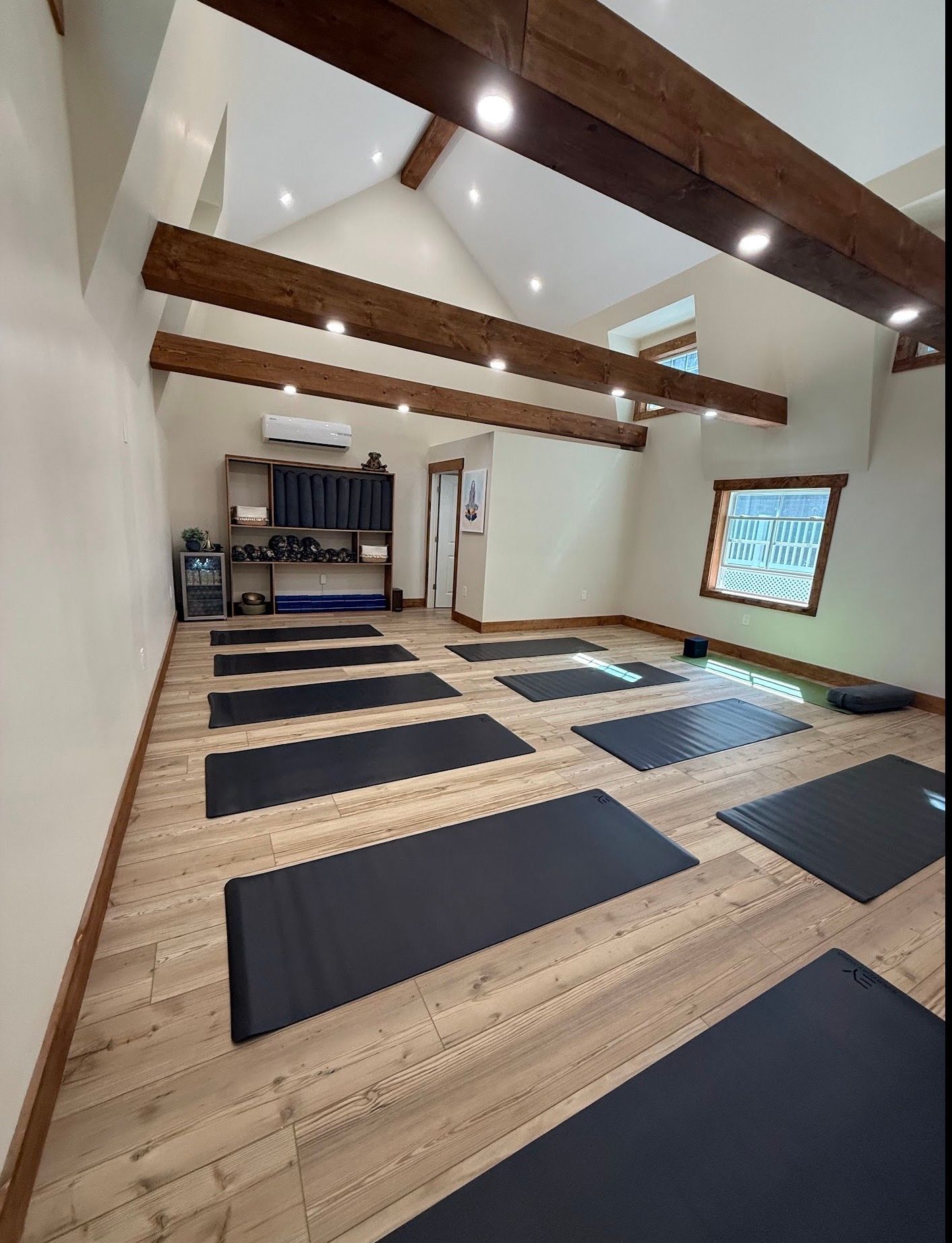 Yoga studio with mats on wooden floor, exposed beams, and natural light.