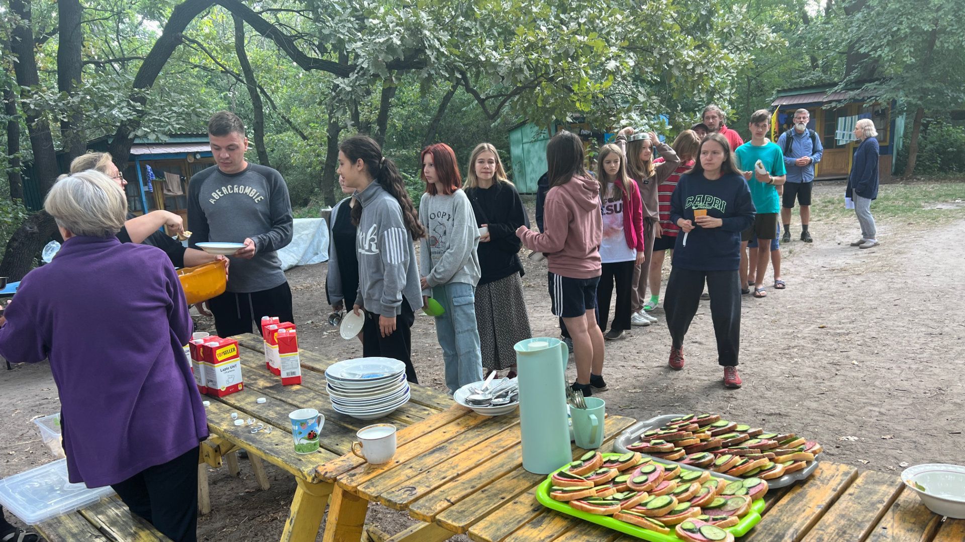 a group of people standing around a picnic table with a man wearing a hollister sweatshirt