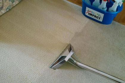 A floor squeegee on beige carpet beside a blue toy bucket.