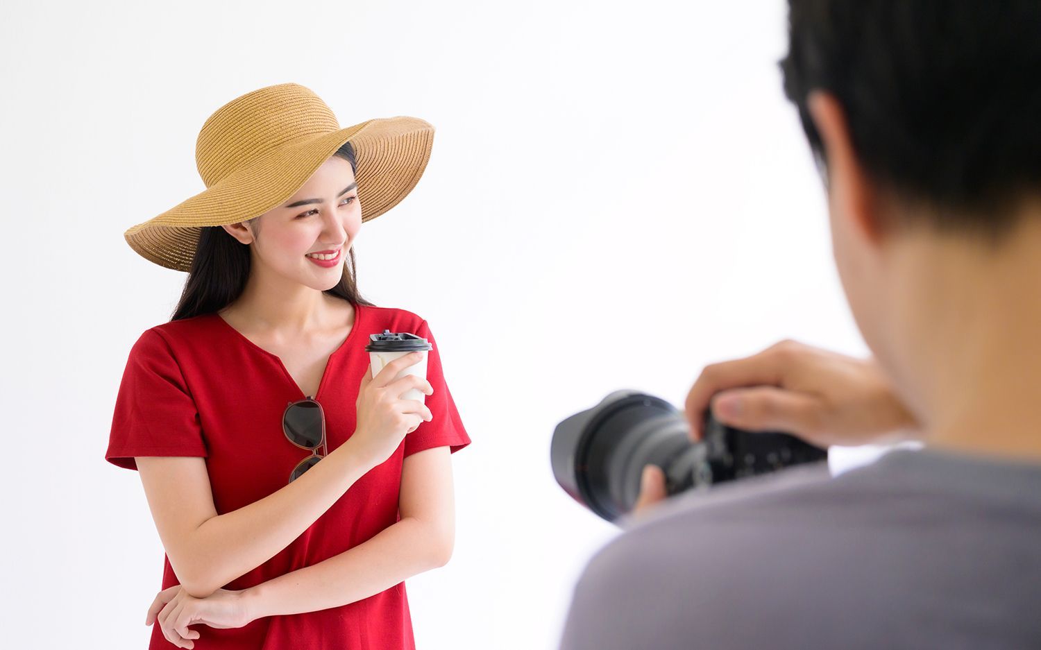 A man is taking a picture of a woman wearing red shirt and a hat