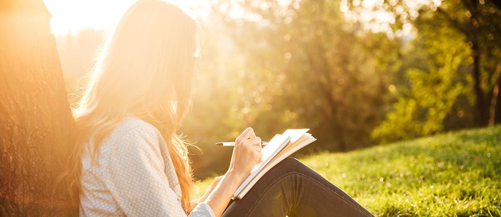 A girl is sitting and writing on a notebook