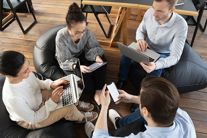 A group of people setting and using phone and laptop