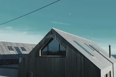 Modern wooden buildings with triangular roof under a blue sky.