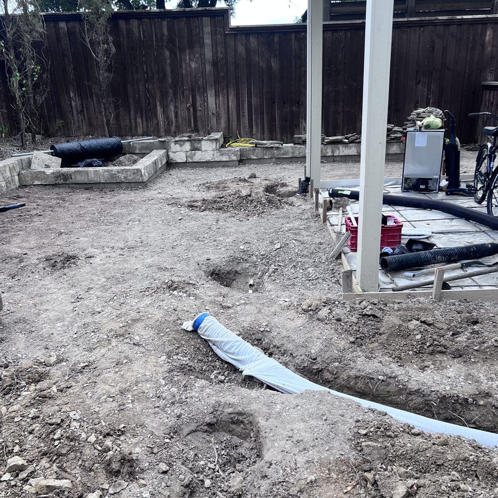 Construction site: Dirt ground with trenches, concrete structures, a fence, and equipment.