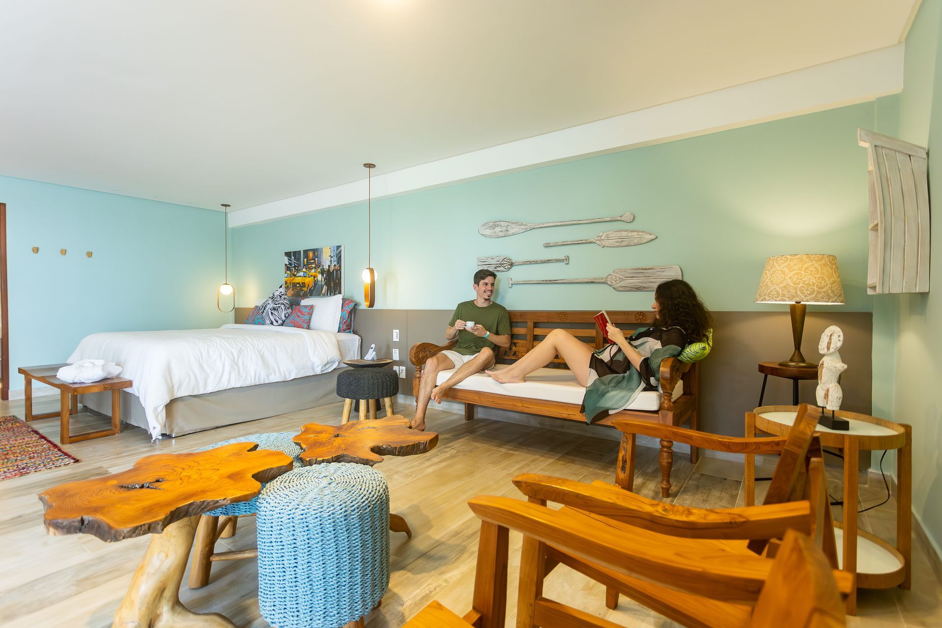 Casal relaxando na acomodação de categoria Master do Armação Resort, em um ambiente espaçoso e decorado com inspiração praiana, com móveis de madeira e detalhes que remetem a uma casa de praia.