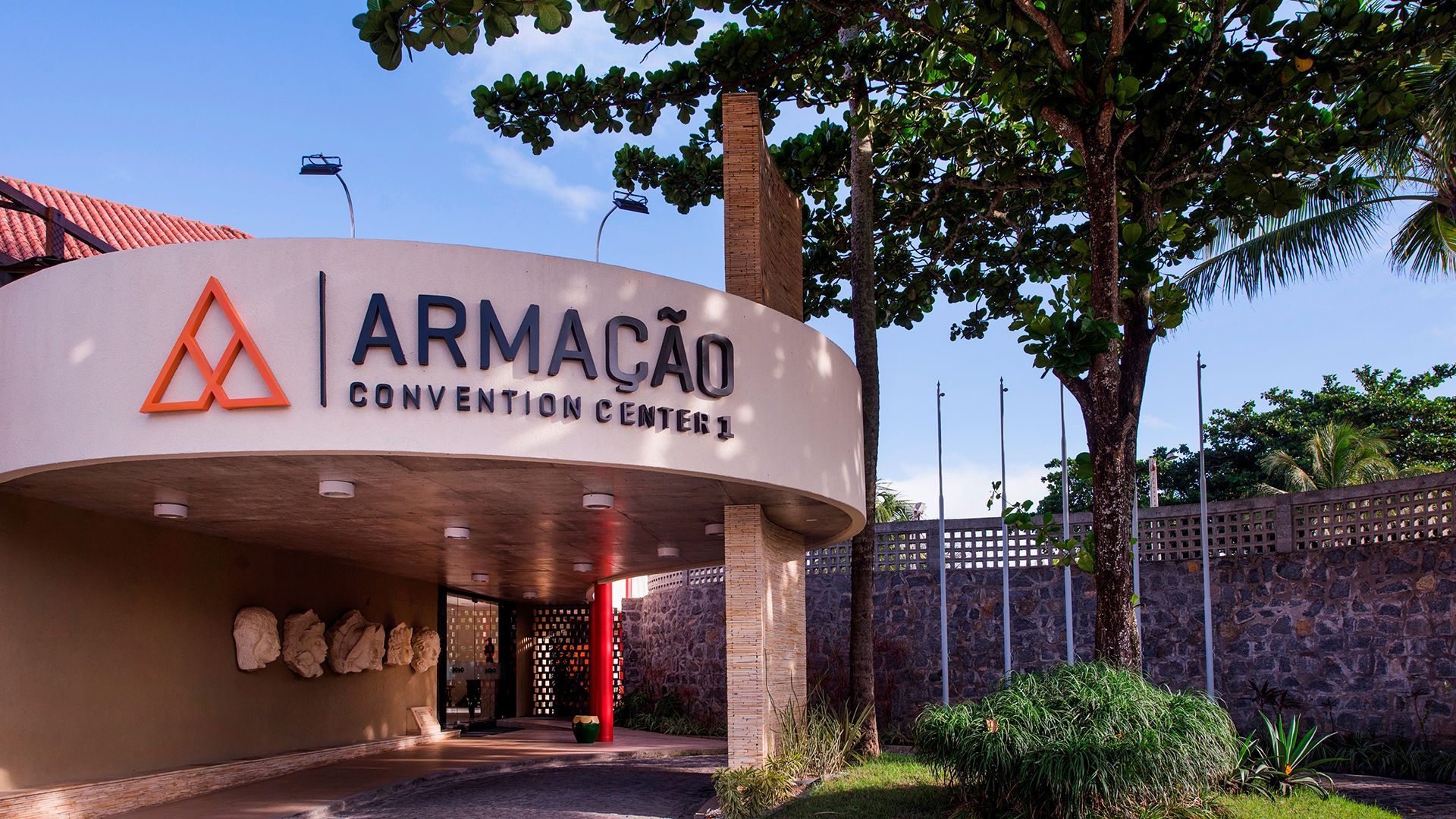 Fachada do Armação Convention Center 1, com uma estrutura moderna e curvada. O letreiro exibe o nome
