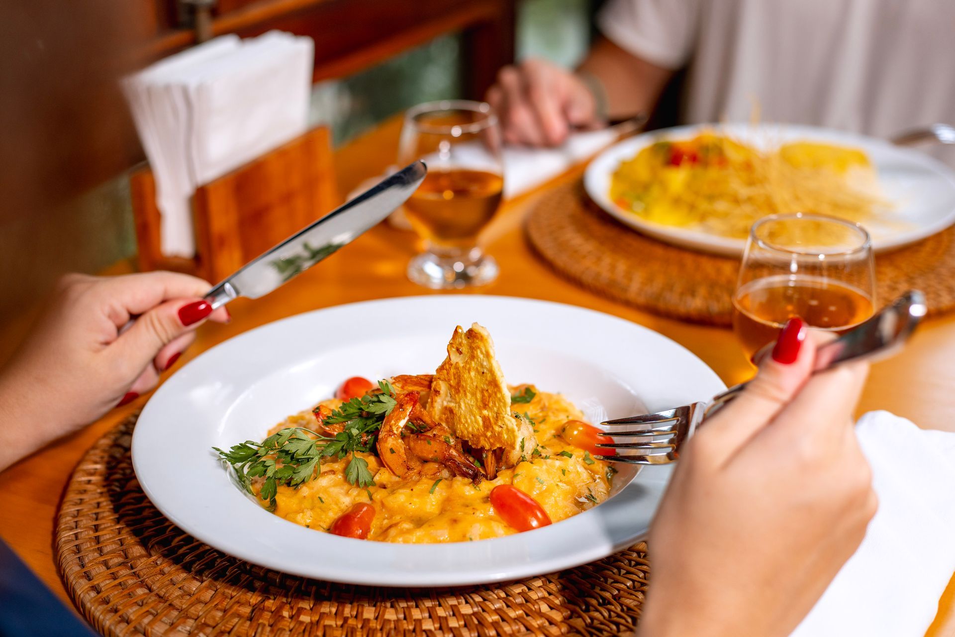 prato de risoto servido à mesa com pessoa segurando talheres durante refeição