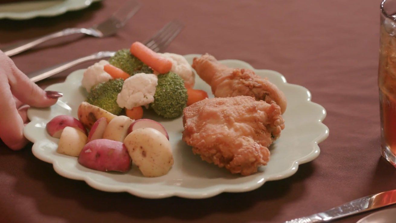 A plate of food with fried chicken , broccoli , potatoes and carrots on a table.